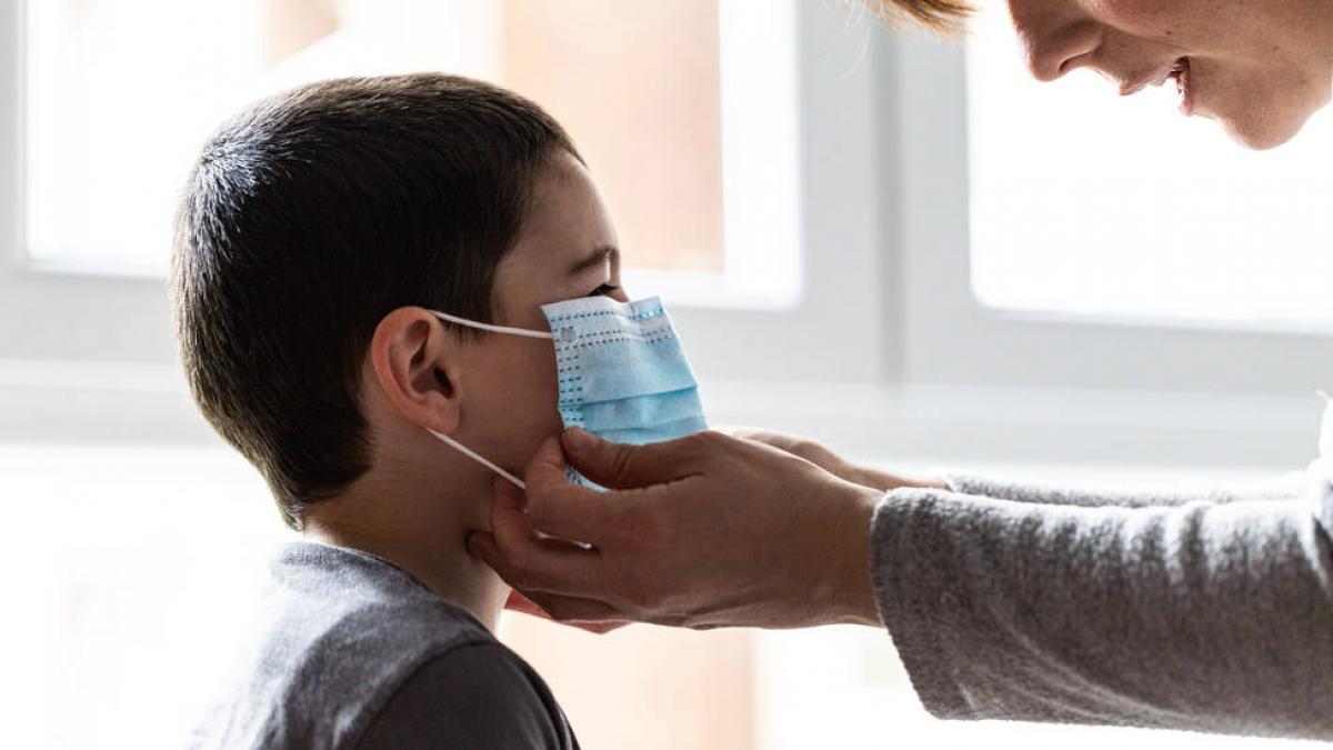 Imagen de un niño y un adulto poniendole una mascarilla. Imagen de un niño y un adulto poniendole una mascarilla.
