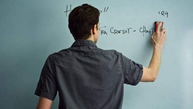 Un profesor escribe en una pizarra durante una clase.