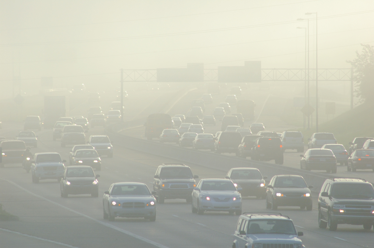 Un atasco de vehiculos bajo una capa de contaminacion.