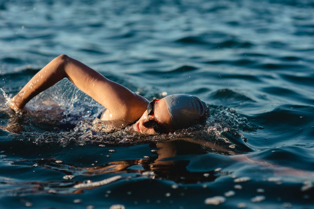 Mujer con gorra y gafas nadando en el mar durante el día